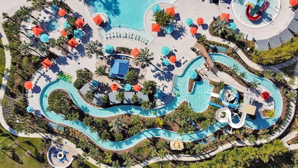 Vue aérienne d’un parc aquatique avec plusieurs piscines, toboggans et chaises longues.
