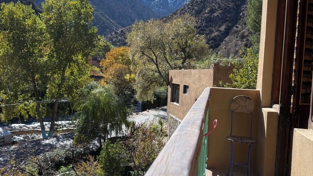 Un balcon donnant sur un paysage montagneux, avec une balustrade en bois et une chaise.
