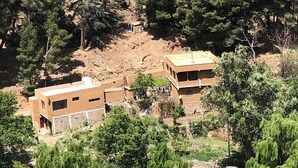 Un quartier résidentiel situé sur une colline, avec deux maisons modernes à deux étages, entourées d’une végétation luxuriante et d’arbres.