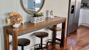 A kitchen with a wooden bar stool set, a large mirror, and a refrigerator. - The Entire Coastal Blue Bliss with heated POOL (Fernandina Beach)