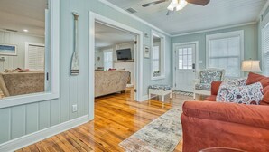 A spacious living room with a wooden floor, a ceiling fan, and a red sofa. - The Entire Coastal Blue Bliss with heated POOL (Fernandina Beach)