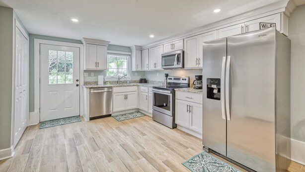 A modern kitchen with white cabinetry, stainless steel appliances, and a large refrigerator. - The Entire Coastal Blue Bliss with heated POOL (Fernandina Beach)