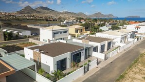 Un quartier résidentiel moderne, avec des maisons contemporaines, des rues bien aménagées et un paysage montagneux en toile de fond.