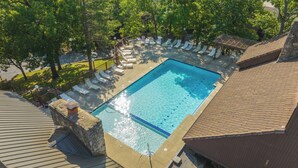 Ein rechteckiger Swimmingpool mit einer gefliesten Kante, umgeben von Liegestühlen und einer Steinmauer.