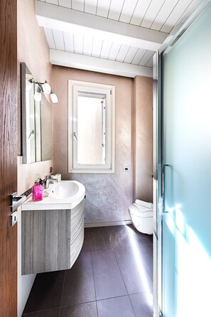 A modern bathroom with a large mirror, a vanity with a sink, and a toilet. - Warda C11 Apartment by Wonderful Italy (Desenzano del Garda)