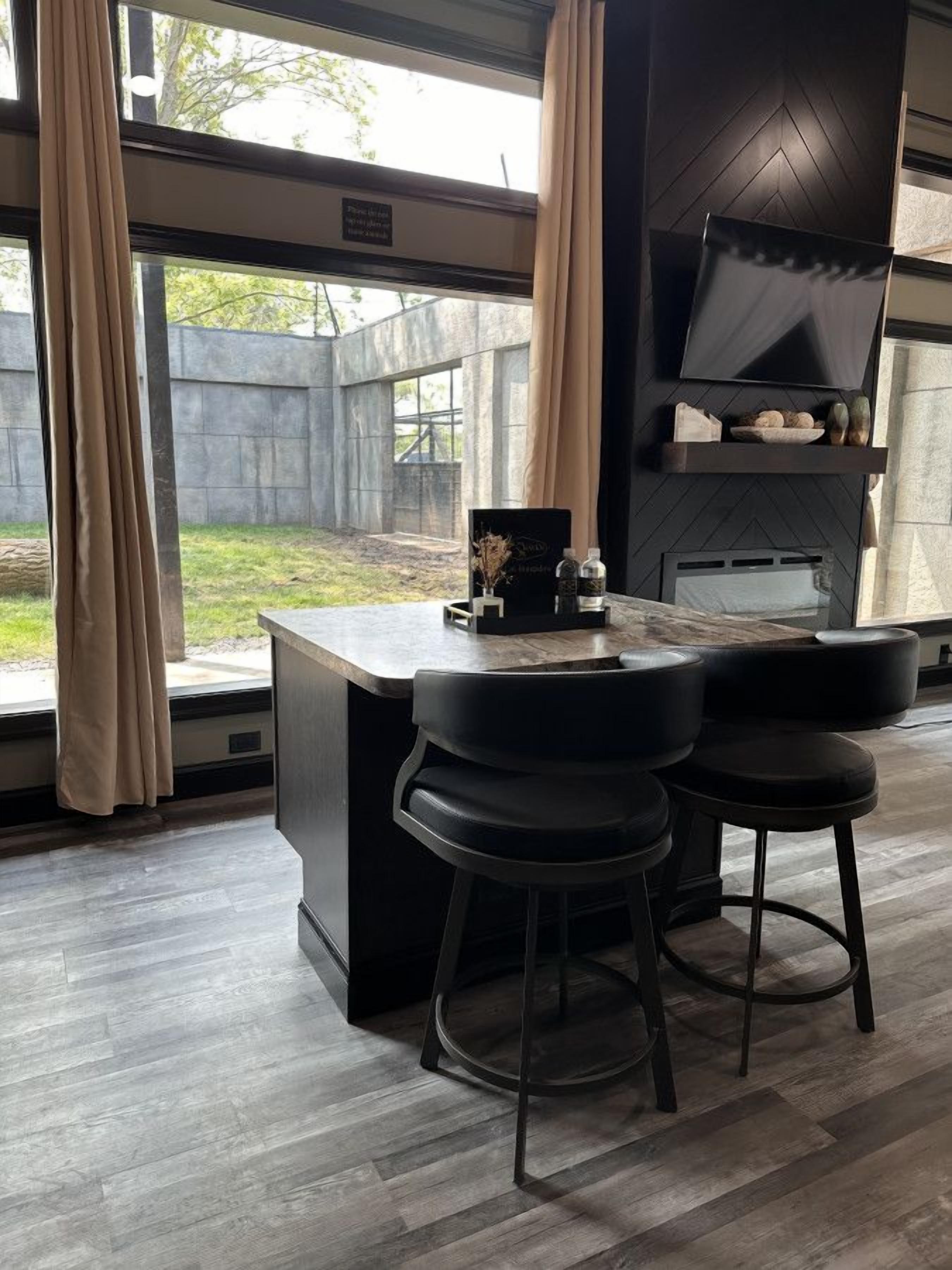 Une cuisine moderne avec un coin bar, de grandes fenêtres et une vue sur le jardin.