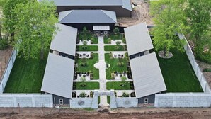 A symmetrical building with a central courtyard, surrounded by trees and a fenced area.
