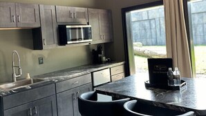 A modern kitchen with dark cabinets, a built-in microwave, a sink, and a bar area with stools.