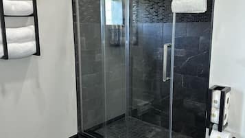 Um banheiro moderno com box de vidro, vaso sanitário branco e porta-toalhas.