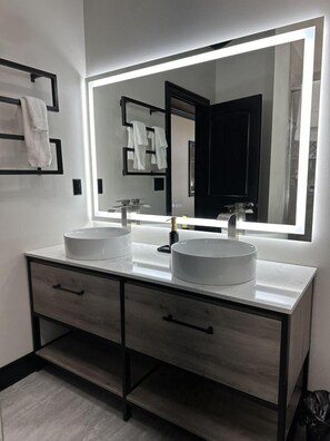 A modern bathroom with two sinks, a large mirror, and a dark-toned vanity with drawers. - Big Cat Bungalows at The Haven - Tiger 3 (Chittenango)