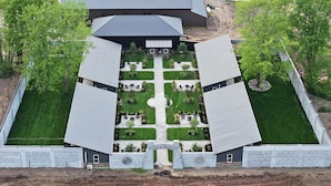 A symmetrical building with a central courtyard, surrounded by a fence, and a paved walkway leading to the entrance.