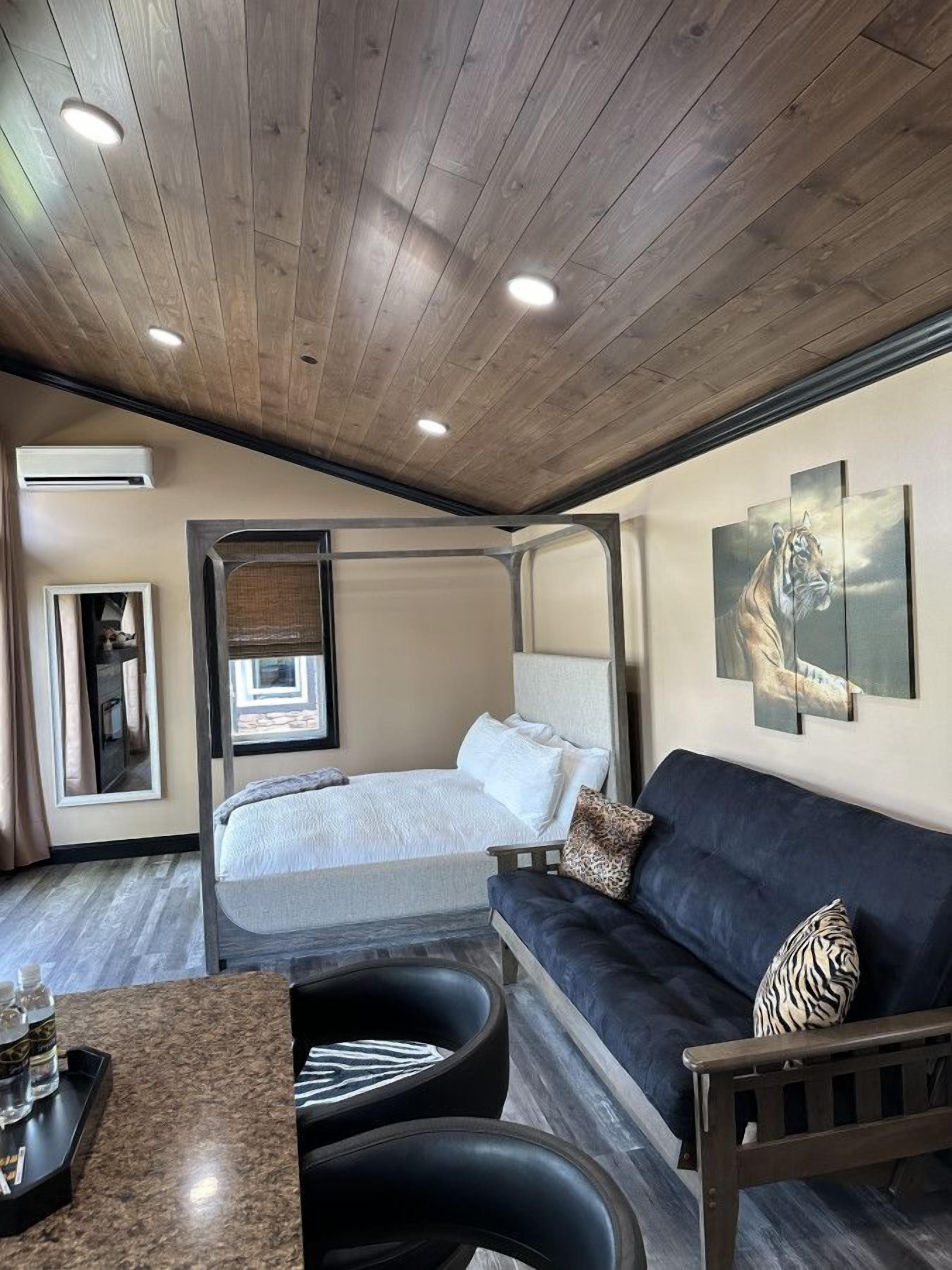 Une chambre à coucher avec un lit, un canapé, une table basse et des œuvres d’art accrochées au mur.