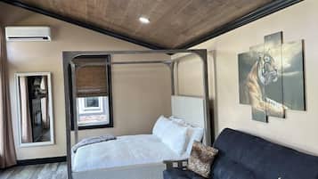Une chambre à coucher avec un lit, un canapé, une table basse et des œuvres d’art accrochées au mur.