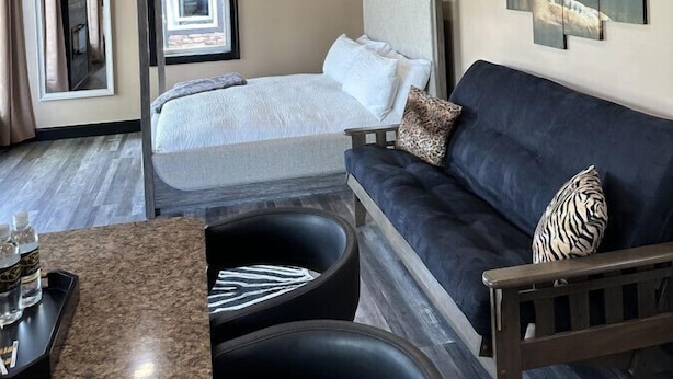 A bedroom with a bed, a sofa, a coffee table, and artwork on the wall.