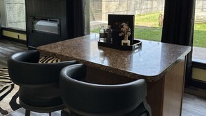 Eine Bar mit zwei schwarzen Barhocker, einer Granit-Arbeitsplatte und Blick auf den Außenbereich durch große Fenster.