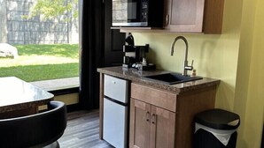 A compact kitchen with a built-in microwave, a coffee maker, and a sink. - Big Cat Bungalows at The Haven - Tiger 4 (Chittenango)