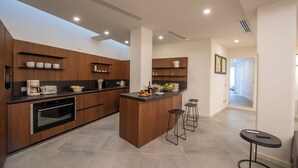A modern kitchen with wooden cabinets, a central island, bar stools, and a small round table. - Villa Corito, luxury villa on the Amalfi coast (Campania)