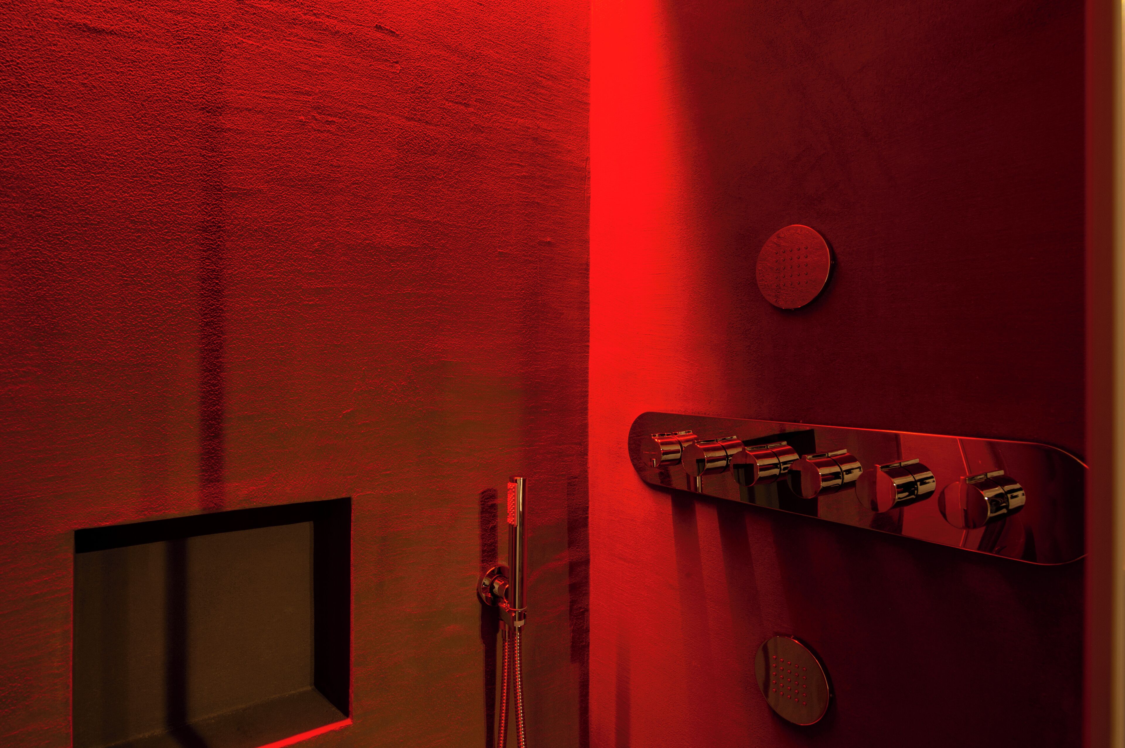 Ein Badezimmer in Rot mit Dusche, Spiegel und Bedienfeld.