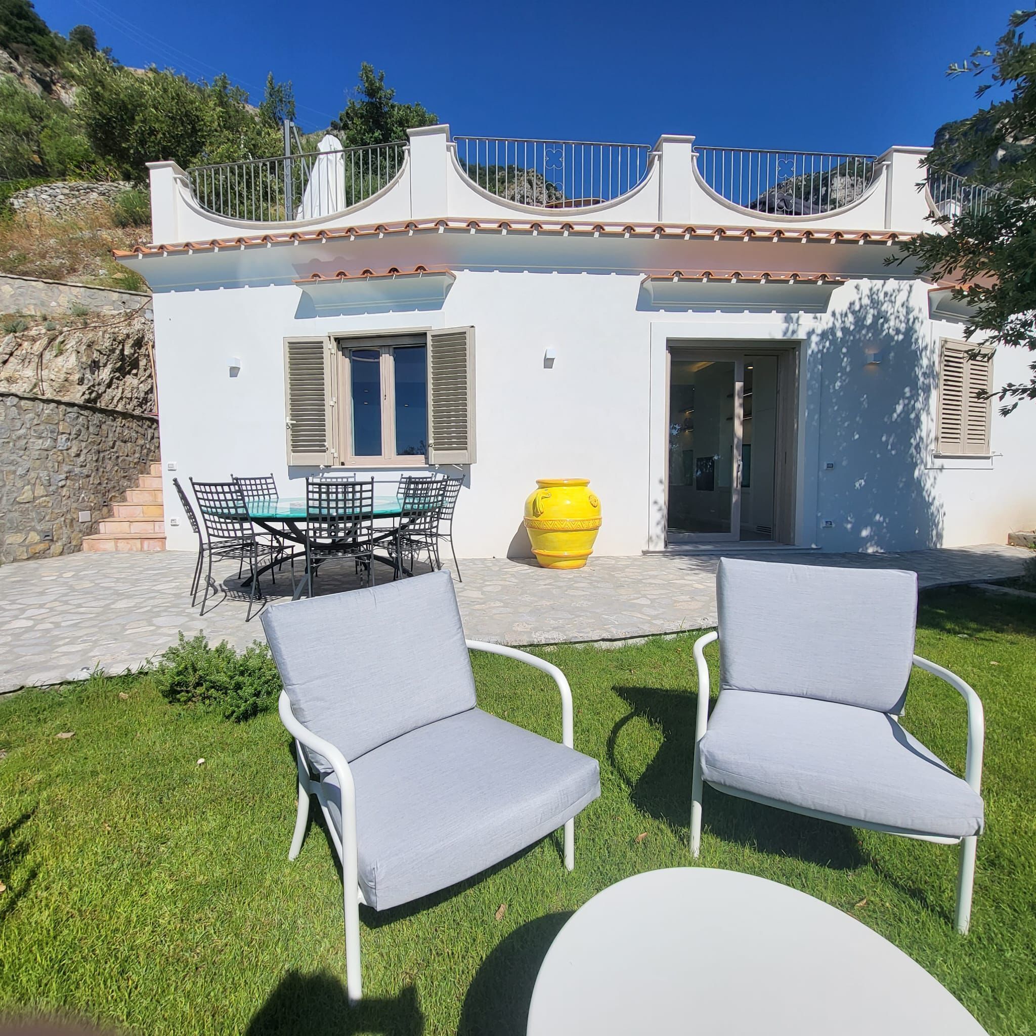 A villa with a patio, outdoor seating, and a stone staircase.