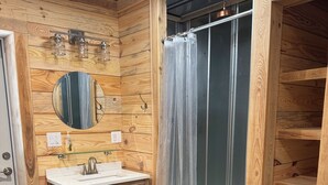 A wooden bathroom with a sink, mirror, and shower curtain. - Barndominium at Dirty Dog Organic Farm (Leesburg)