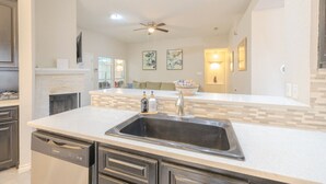 A modern kitchen with a central island, dark cabinetry, and a dishwasher. - Private Indoor Swimming Pool (The Colony)
