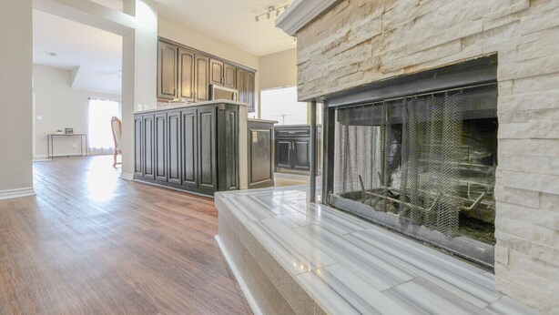 A spacious living room with a stone fireplace, dark wooden cabinets, and a large island. - Private Indoor Swimming Pool (The Colony)