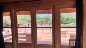 A wooden door with three windows, a sign prohibiting horse feeding, and a view of a fenced outdoor area with a vehicle and buildings. - Les Chalets de Tesa N°2 Luxe, Calme et Nature (Occhiatana)