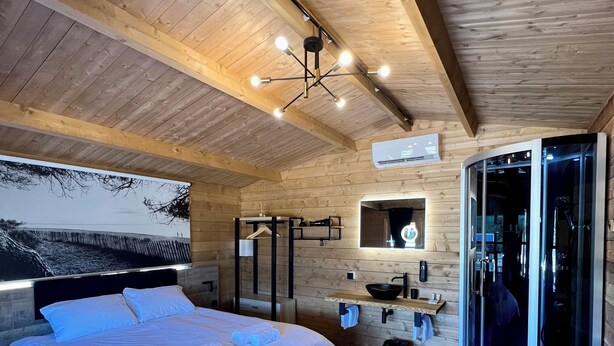 A modern bedroom with a large bed, a wooden ceiling, and a glass shower enclosure. - Les Chalets de Tesa N°2 Luxe, Calme et Nature (Occhiatana)