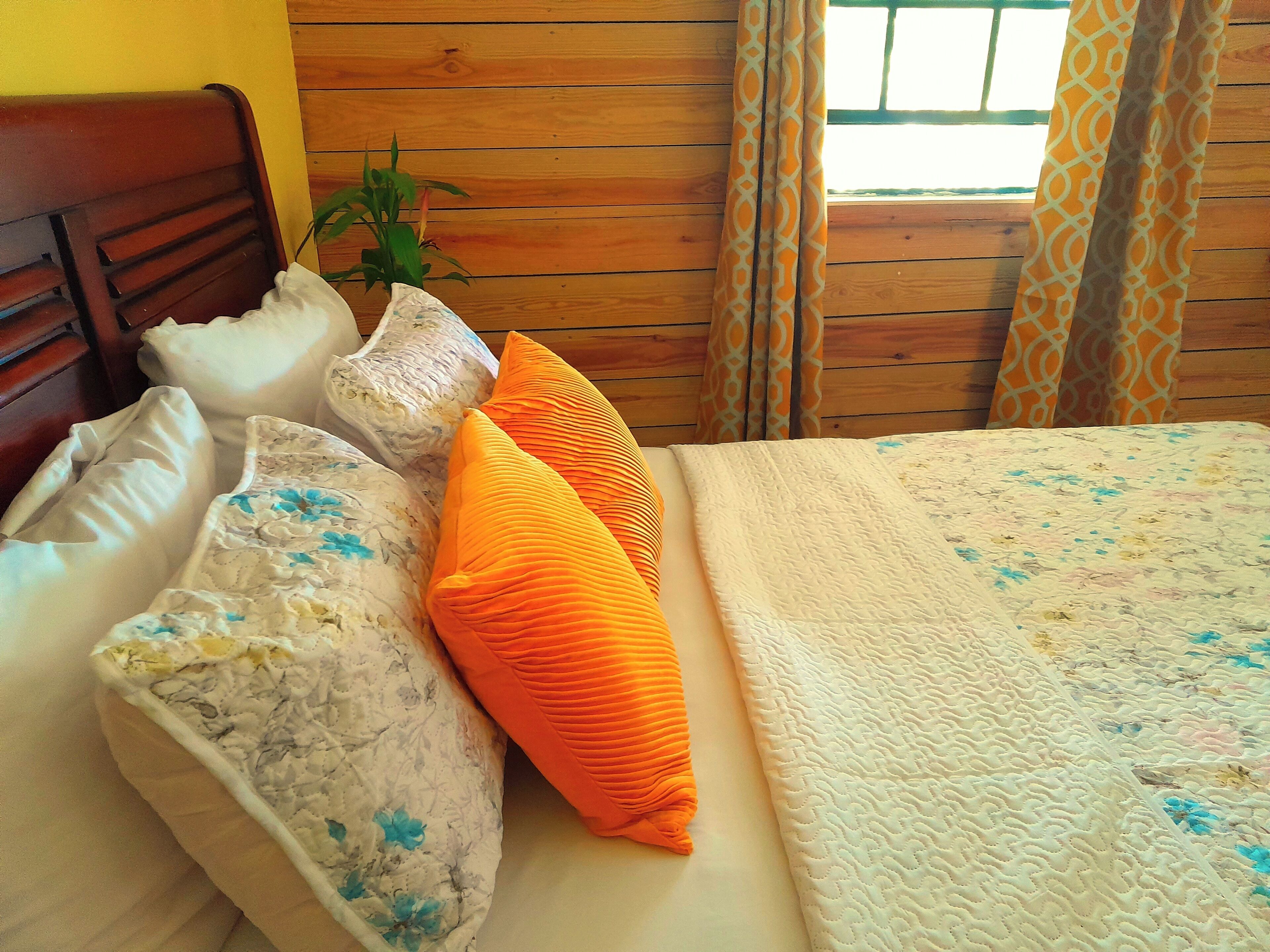 Una cama con almohadas de estampado floral, una colcha y un cabecero de madera.