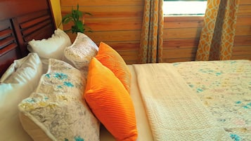 Una cama con almohadas de estampado floral, una colcha y un cabecero de madera.