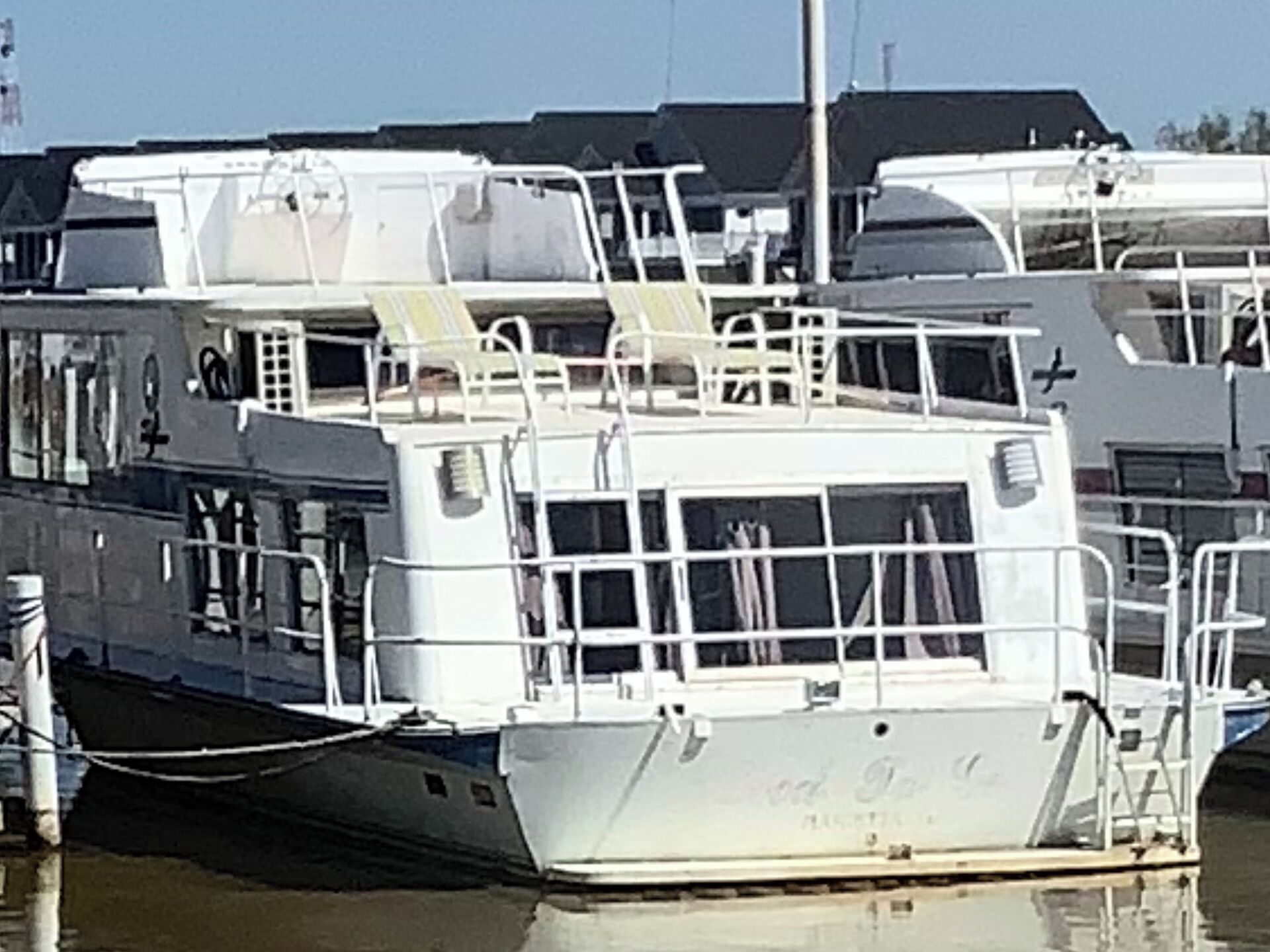 Un barco blanco amarrado en un puerto deportivo con varias cubiertas y barandillas.