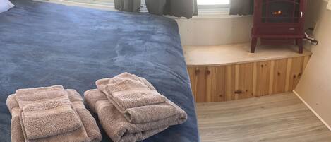 Een bed met een blauwe spreidek en twee opgevouwen handdoeken.