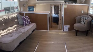 A compact RV interior with a sofa, a chair, a television, and a sign indicating a lake view.