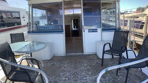 A boat's deck with a glass table and chairs, a "Welcome" sign, and a "Good to Go" sign.