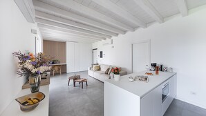 A modern kitchen with a central island, a dining area with a table and chairs, and a living room with a sofa and a coffee table. - La Cittadella PT-6 by Wonderful Italy (Manerba del Garda)