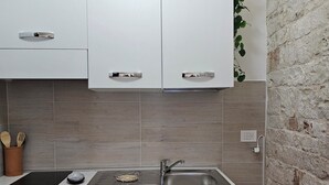 A modern kitchen with white cabinets, a stainless steel sink, and a built-in oven. - PietraRosa Apartment (Triggianello)