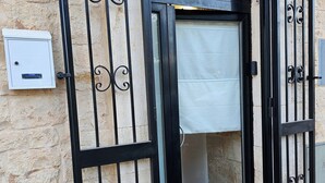 A black metal gate with decorative scrollwork, a white electrical box, and a stone wall. - PietraRosa Apartment (Triggianello)