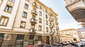 Un edificio a più piani con balconi, auto parcheggiate e un cartello per l'Ufficio Postale di Cambio.