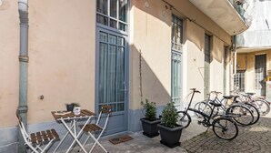 Un cortile con un tavolo e sedie, piante in vaso e biciclette appoggiate a un edificio.