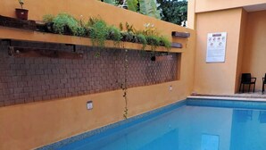 A swimming pool with steps leading into it, a brick wall, and a sign on the wall. - Cancun International by ZEIVA (Cancun)