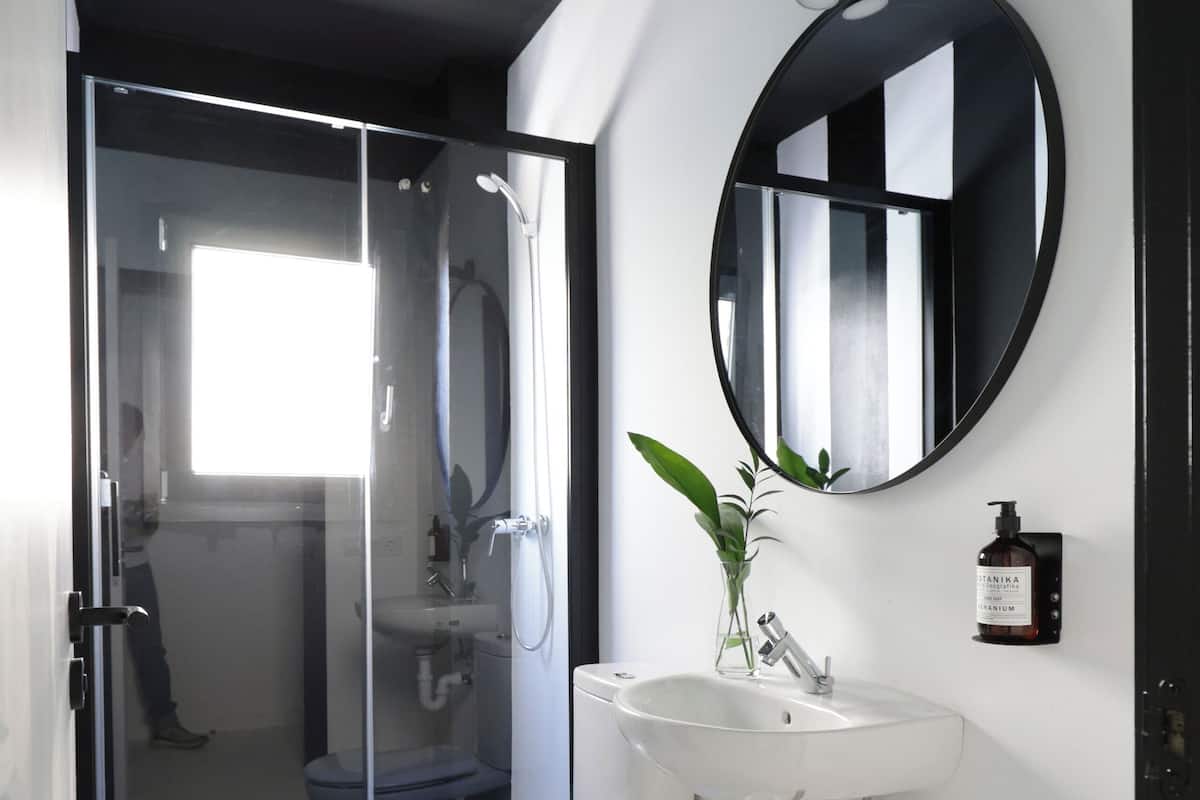A modern bathroom with a glass shower enclosure, a white toilet, a sink, and a mirror.