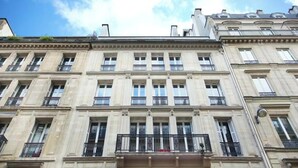Un edificio a più piani con stile architettonico classico, caratterizzato da una facciata simmetrica con finestre e balconi regolarmente distanziati.