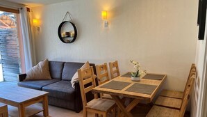 Un salon chaleureux avec un canapé, des chaises en bois, une table à manger et une petite plante en pot.