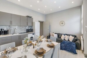 A modern kitchen with grey cabinets, a tiled backsplash, and a dining area with a table set for four.