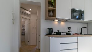 A modern kitchen with white cabinets, a microwave, and a countertop with a kettle and a pot. - Lake River Apartment (Lecco)