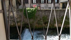 A view of a river with a bridge in the foreground and buildings in the background. - Lake River Apartment (Lecco)
