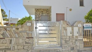 A modern building with a stone facade, numbered signs, and a metal gate. - Villa Lara (Torre Pali)