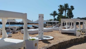 Ein Strandresort mit weißen Liegestühlen, einem Pool und Palmen.
