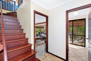 A wooden staircase leading to a room with a glass door, a tiled floor, and a view of an outdoor patio area.