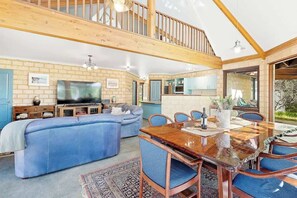 A spacious living area with a large sofa, a dining table, and a kitchen in the background.